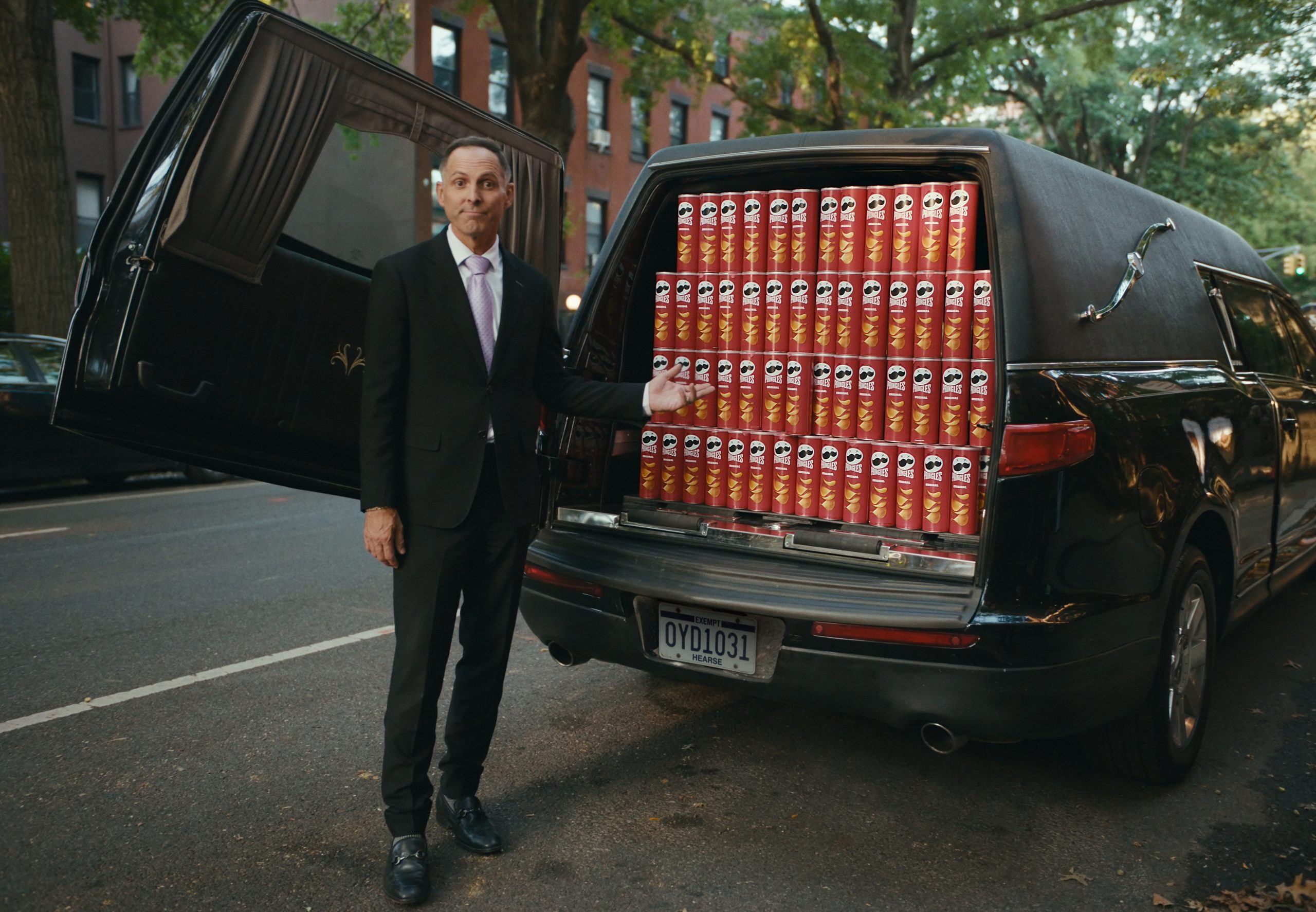 Dan the Funeral Man standing in front of hearse full of Pringles